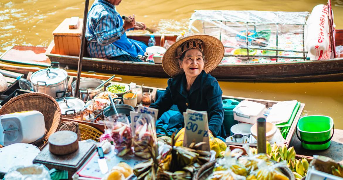 Signora con bancarella su barca in Thailandia