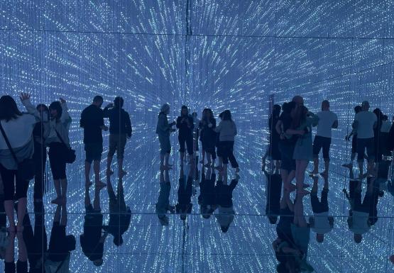 Visitors walking through LED light tunnel at teamLab Planets