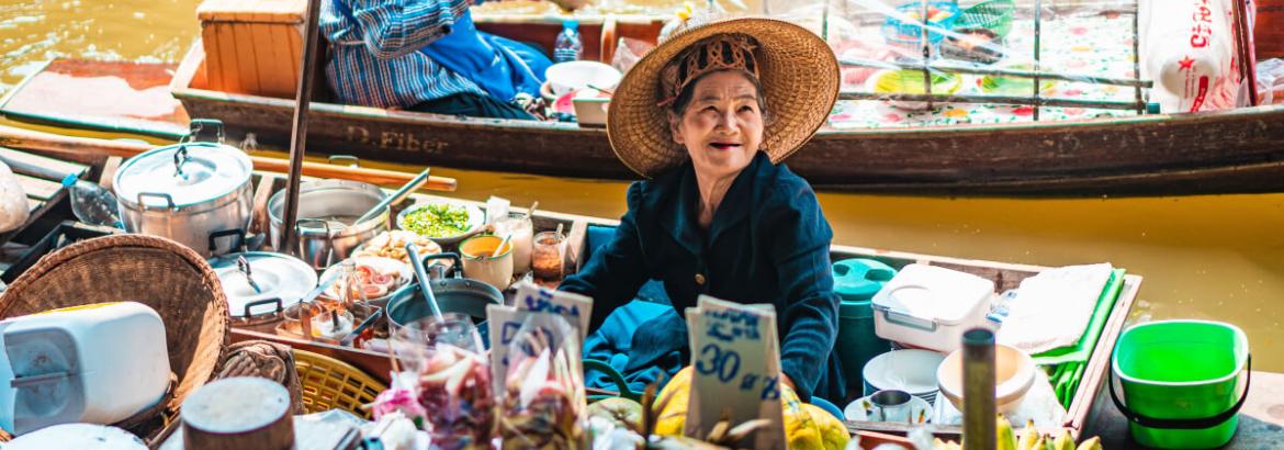 Signora con bancarella su barca in Thailandia