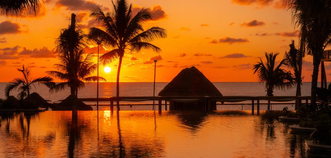 cancun rivera maya spiaggia tropicale al tramonto con palme e palafitta sul mare